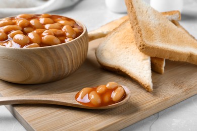 Photo of Toasts and delicious canned beans on white table, closeup