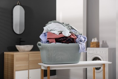 Laundry basket filled with clothes on table in bathroom