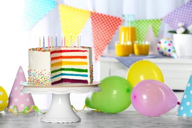 Photo of Delicious rainbow cake with candles for party on table