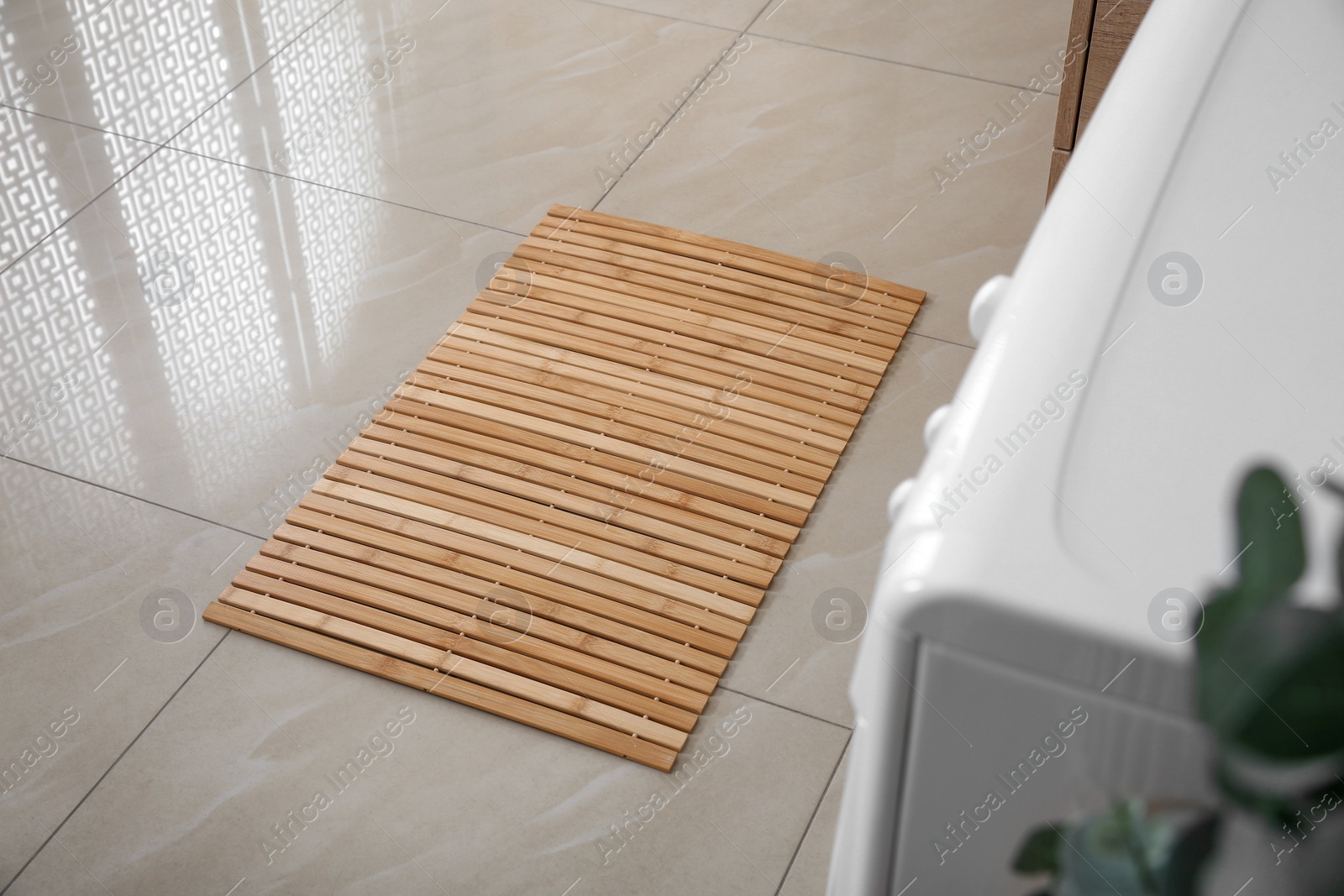 Photo of Wooden mat on floor near washing machine in bathroom