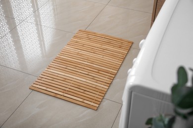 Photo of Wooden mat on floor near washing machine in bathroom