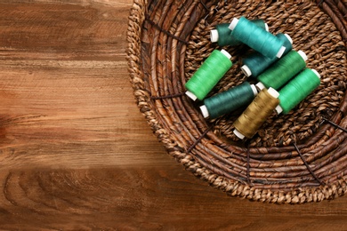 Basket with set of color sewing threads on wooden background