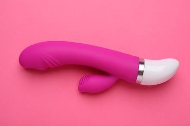 Photo of Vaginal vibrator on pink background, top view. Sex toy