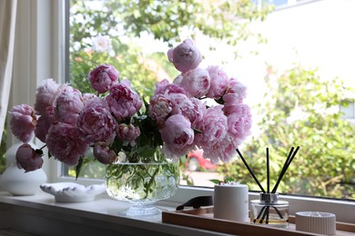 Photo of Beautiful pink peonies in vase on window sill. Interior design