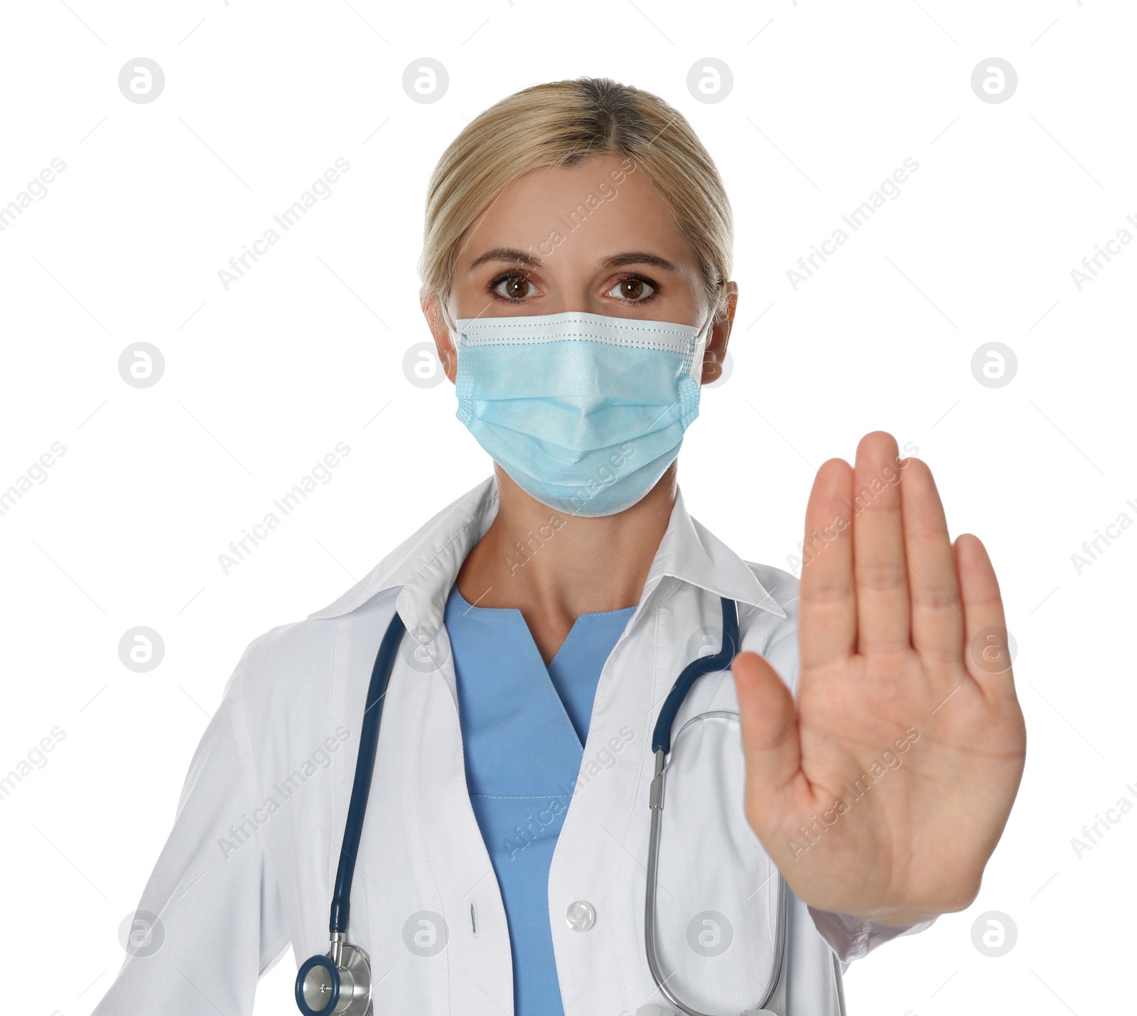 Photo of Doctor in protective mask showing stop gesture on white background. Prevent spreading of coronavirus