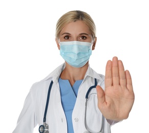 Doctor in protective mask showing stop gesture on white background. Prevent spreading of coronavirus