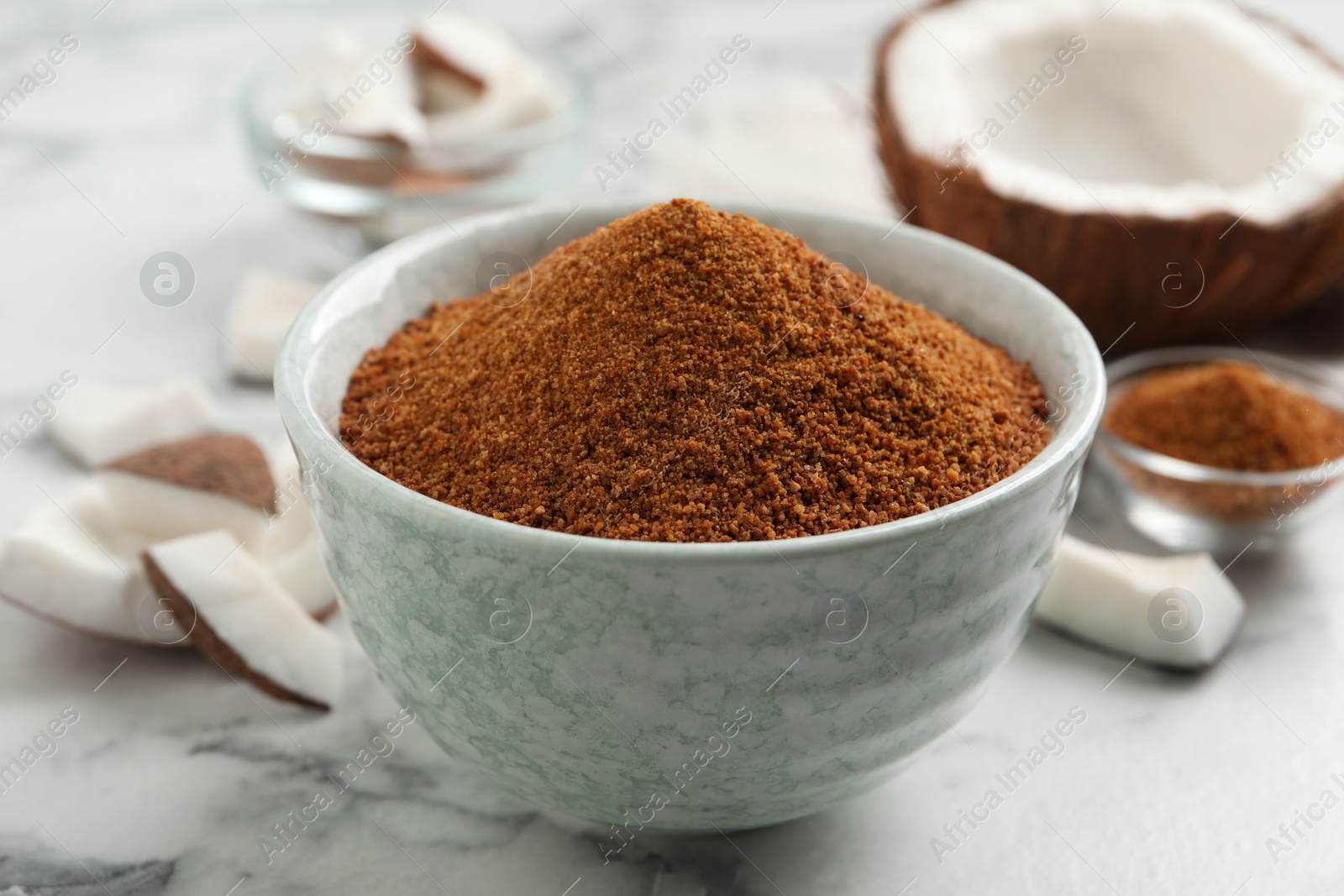 Photo of Natural coconut sugar in ceramic bowl on white marble table