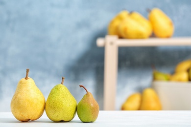 Photo of Fresh ripe pears on light table against blurred background. Space for text