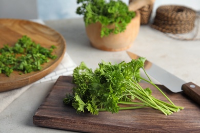 Wooden board with fresh green parsley on table