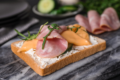 Delicious sandwich with ham on marble table, closeup