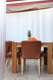 Photo of Wooden table with fruits and stylish chairs on terrace