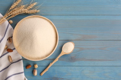 Photo of Uncooked organic semolina, spikelets and nuts on light blue wooden table, flat lay. Space for text