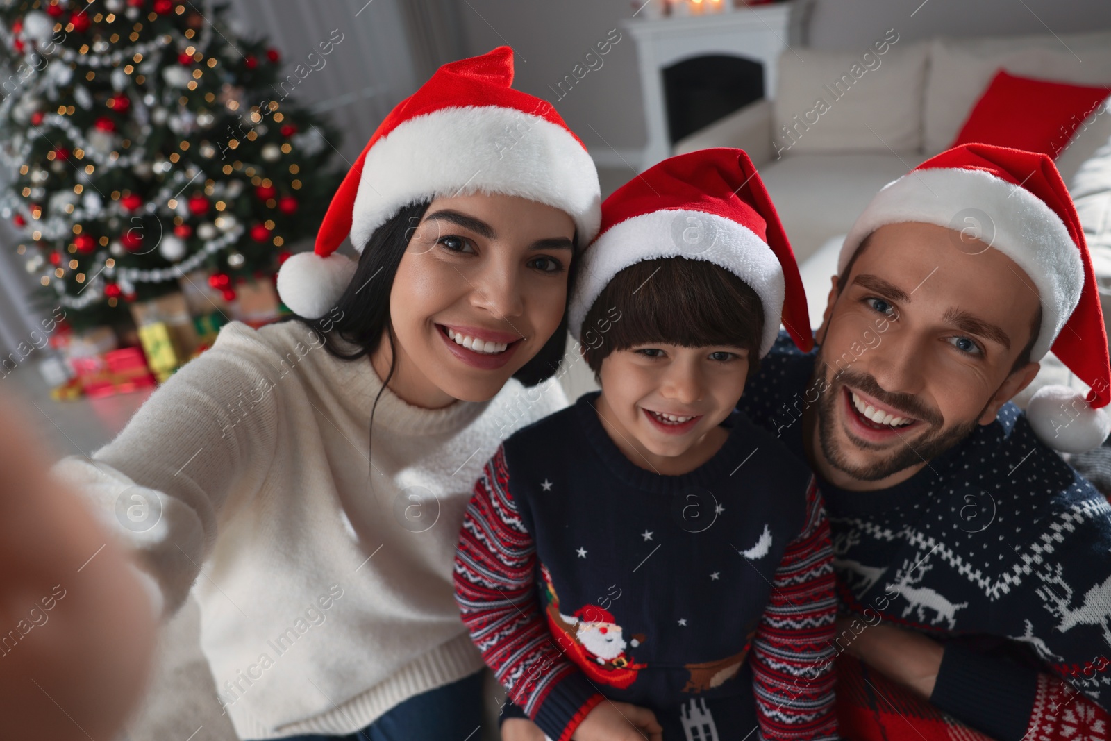 Photo of Happy family in Santa hats taking selfie at home. Christmas celebration