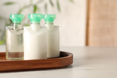 Photo of Mini bottles of cosmetic products on white table against blurred background. Space for text