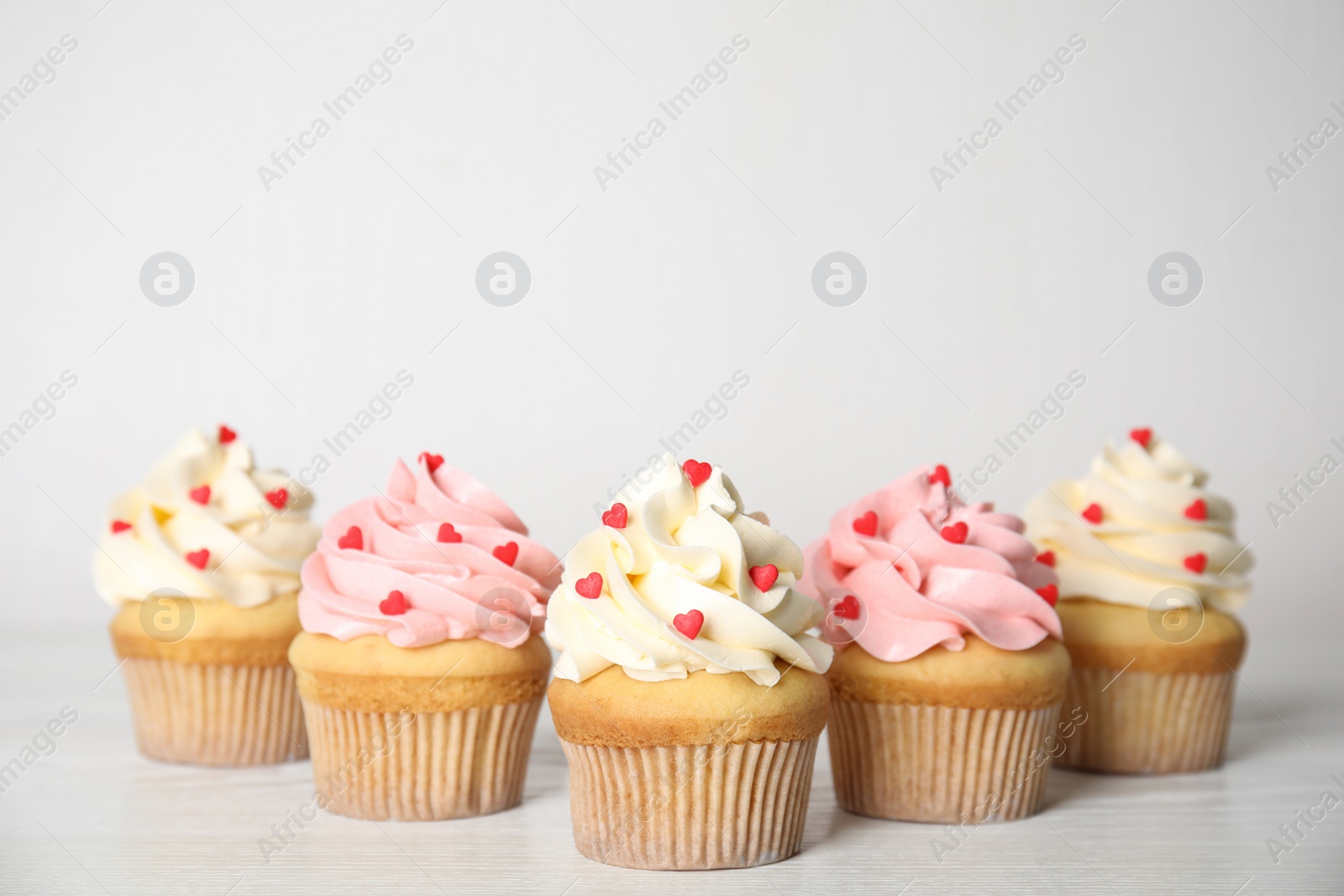 Photo of Tasty sweet cupcakes on white table. Happy Valentine's Day