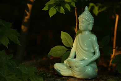 Decorative Buddha statue on stone under tree, space for text