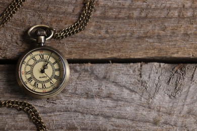 Photo of Pocket clock with chain on wooden table, top view. Space for text