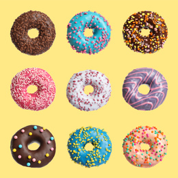 Image of Set with delicious glazed donuts on yellow background