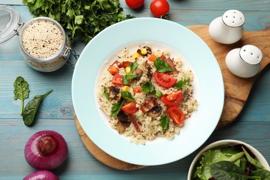 Photo of Plate of tasty quinoa porridge with fried bacon, mushrooms and vegetables on light blue wooden table, flat lay