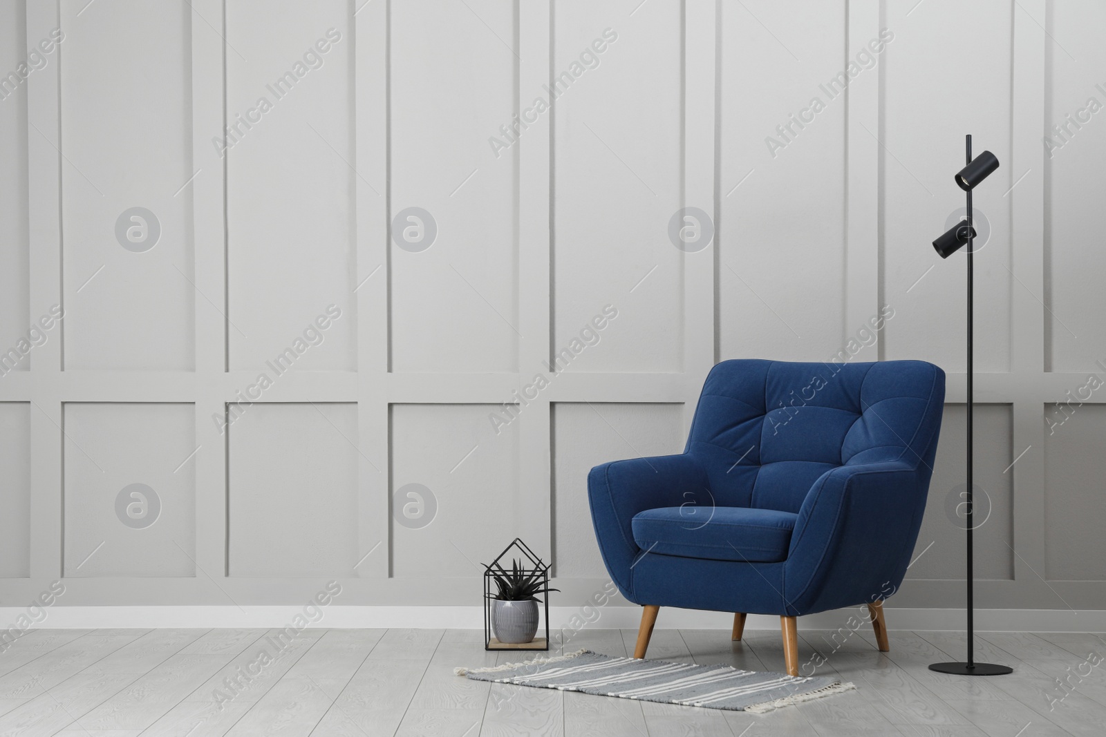 Photo of Stylish interior with armchair and floor lamp near white wall in room, space for text