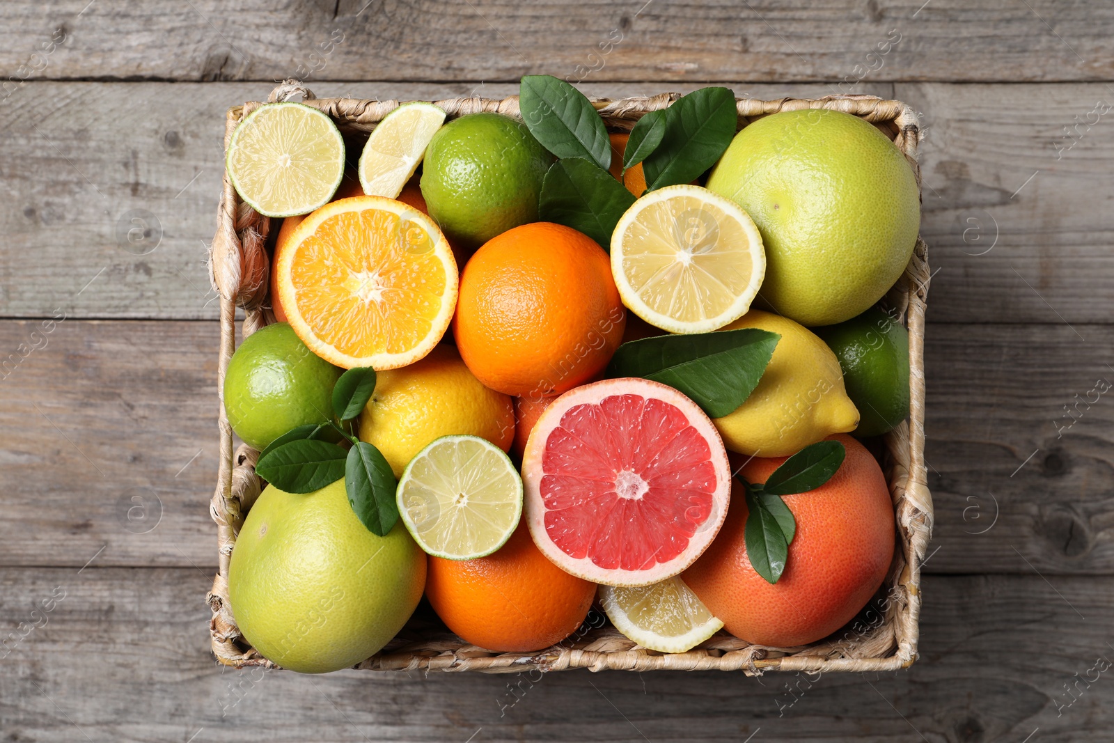 Photo of Different cut and whole citrus fruits on wooden table, top view