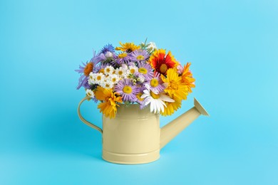 Photo of Yellow watering can with beautiful flowers on light blue background