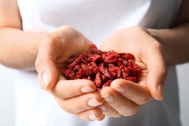 Photo of Woman holding red dried goji berries, closeup