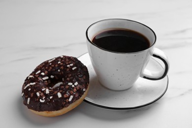 Photo of Tasty donut and cup of coffee on white marble table