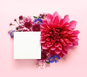 Flat lay composition with beautiful dahlia flowers and blank card on color background