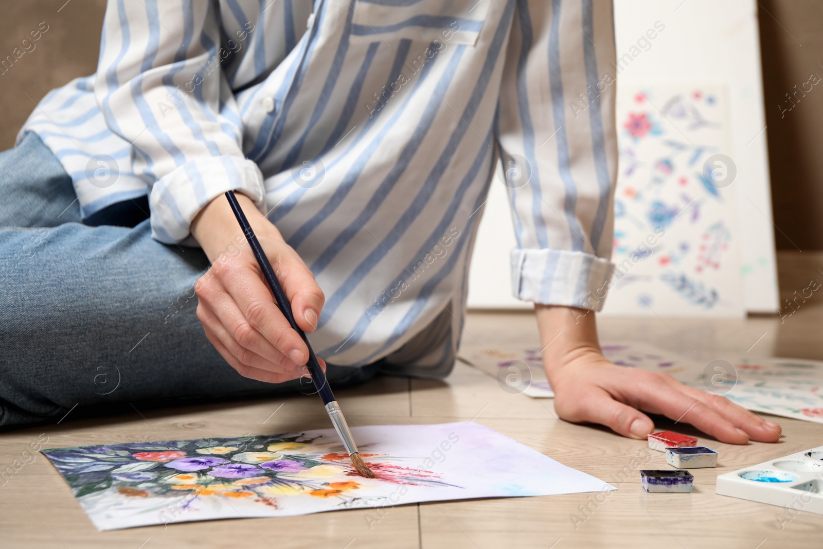 Photo of Woman painting flowers with watercolor on floor, closeup