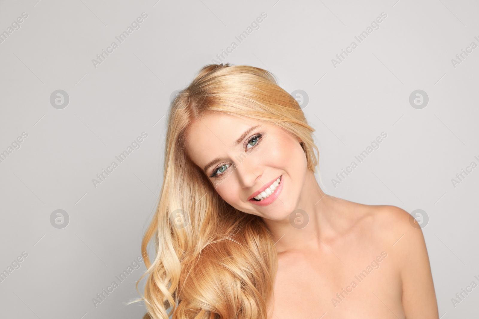 Photo of Beautiful woman with healthy long blonde hair on light background