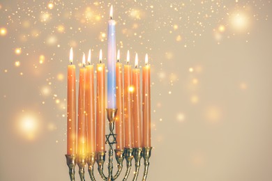 Hanukkah celebration. Menorah with burning candles on beige background, closeup. Space for text
