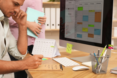 Colleagues working with calendar app on computer in office, closeup