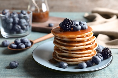 Photo of Tasty pancakes with berries and syrup on plate