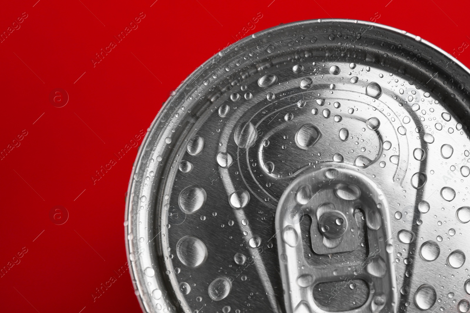 Photo of Energy drink in wet can on red background, top view