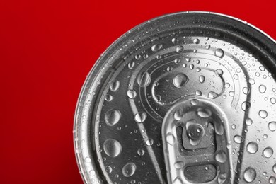 Photo of Energy drink in wet can on red background, top view