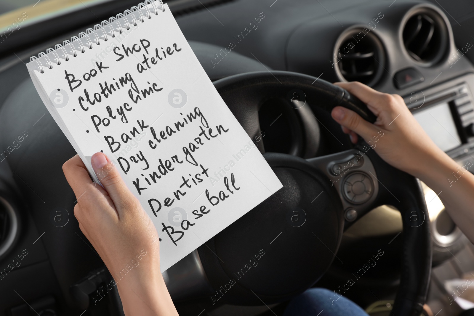 Photo of Woman with to do list in driver's seat of car, closeup. Stress overload concept