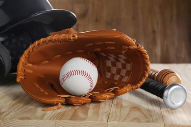 Photo of Baseball glove, bats, ball and batting helmet on wooden table