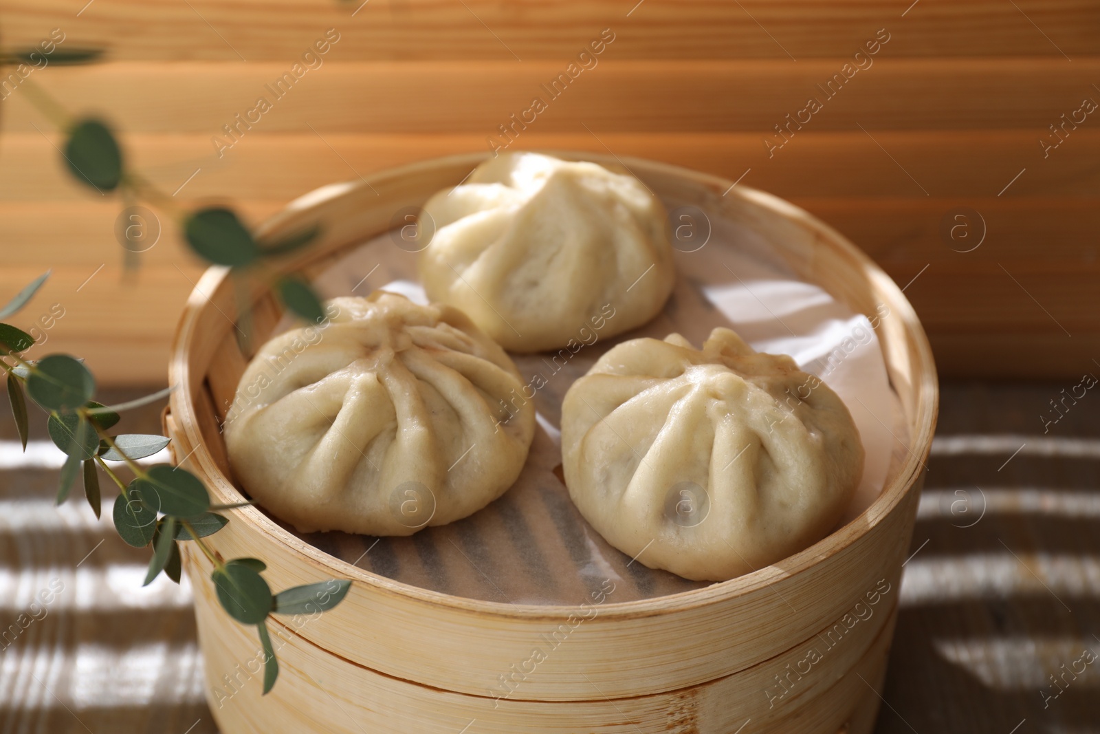 Photo of Delicious bao buns (baozi) on wooden table, closeup