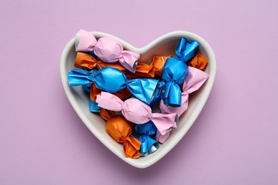 Candies in colorful wrapper on pink background, top view