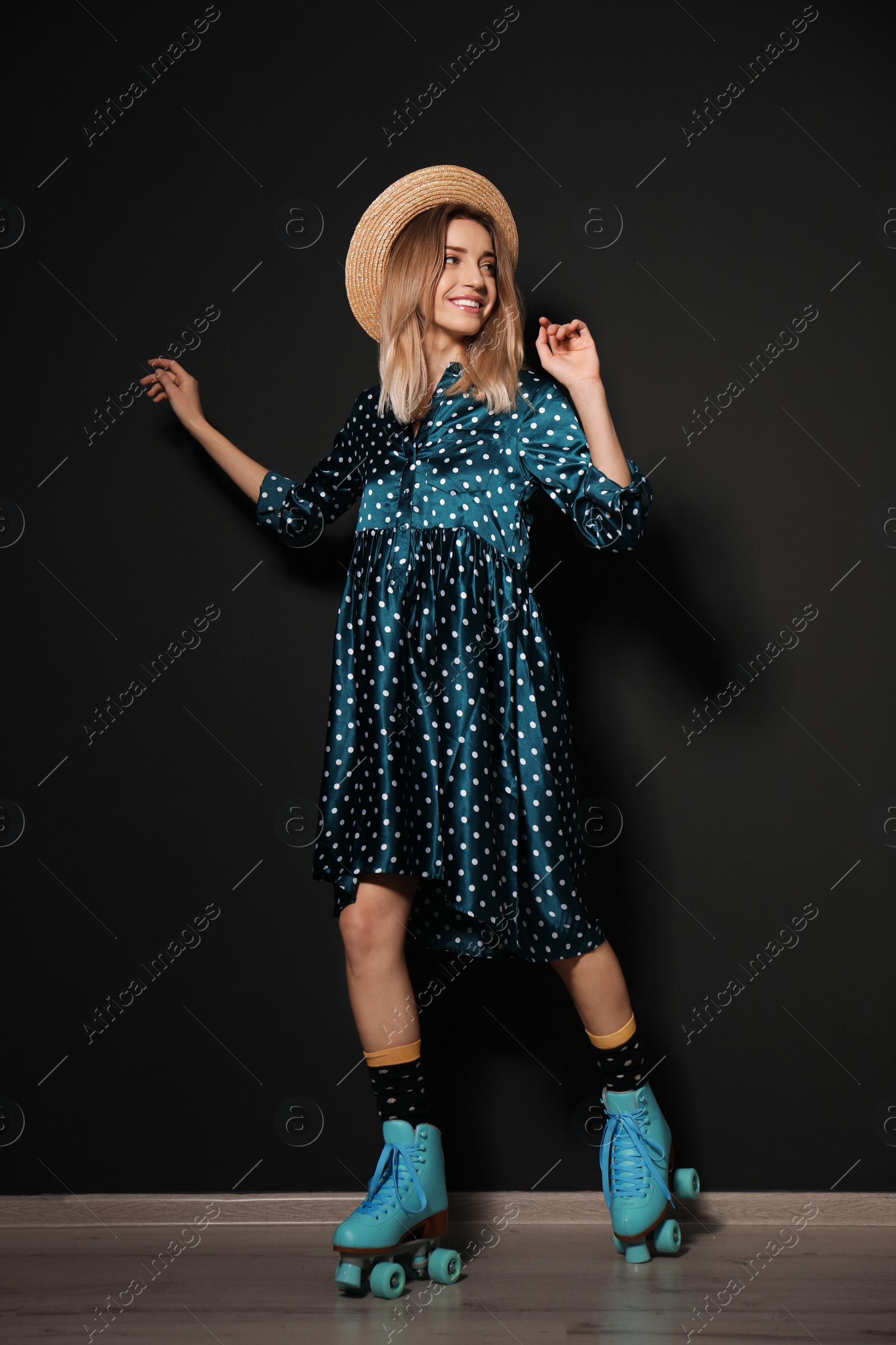 Photo of Young woman with retro roller skates against black wall