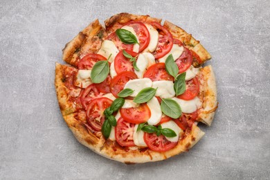 Photo of Delicious Caprese pizza with tomatoes, mozzarella and basil on light grey table, top view