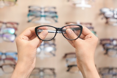 Female ophthalmologist with glasses near showcase in optical store