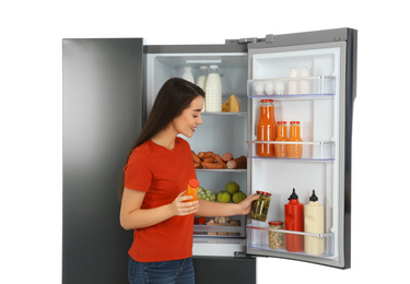 Photo of Young woman choosing products from refrigerator on white background