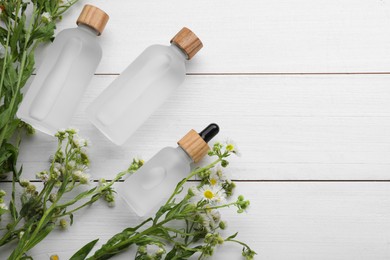 Photo of Bottles of essential oil with chamomile flowers on white wooden table, flat lay. Space for text
