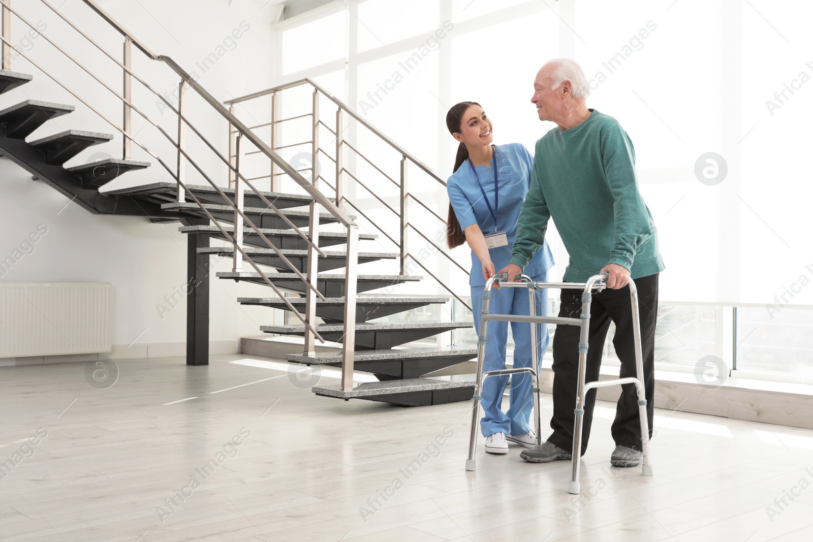 Photo of Nurse assisting senior man with walker in hospital