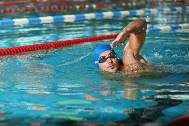 Photo of Young athletic man swimming in pool indoors