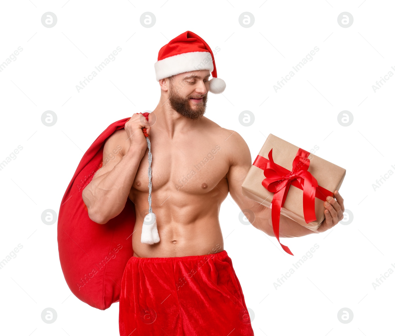 Photo of Attractive young man with muscular body in Santa hat holding bag and Christmas gift box on white background