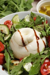 Photo of Delicious burrata salad with arugula, tomatoes and cucumbers, closeup