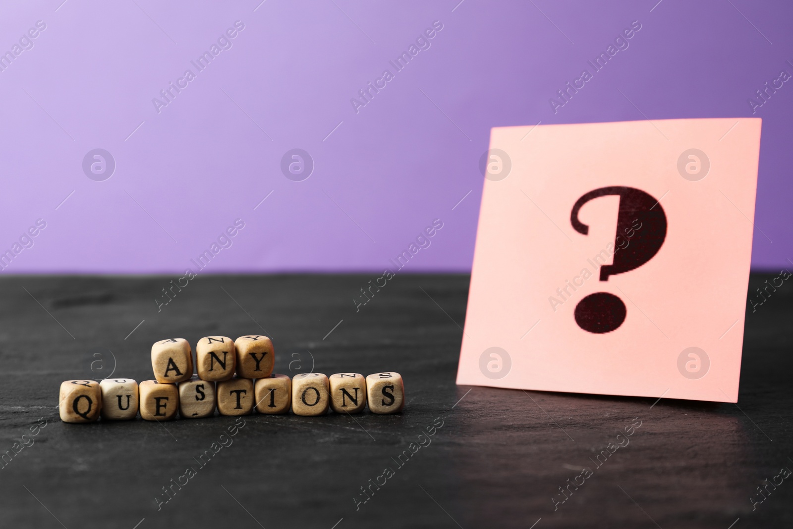 Photo of Phrase Any Questions made of wooden cubes and note with punctuation mark on black stone table